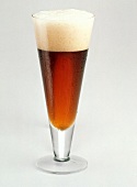 Ein Glas dunkles Bier mit Schaum
