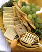 Käsescheiben und Cracker mit Trauben, Käsestangen auf Teller