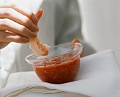 hand About to Dip a Shrimp into Cocktail Sauce