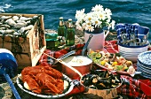 Picknick mit Meeresfrüchtegerichten, Bier und Blumen am Meer