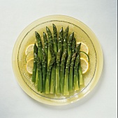 Gekochter grüner Spargel mit Zitronenscheiben auf Teller