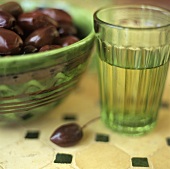 Oliven neben einem Glas Wasser