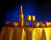 Tischdeko aus goldenen Früchten, Weinflasche und Gläsern