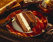 Slice of chocolate & vanilla layer cake; brandy glass; old books
