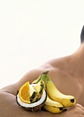 Kokosnuss und exotische Früchte auf Arm eines Mannes
