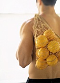 Gesundheit mit Vitamin C: Muskulöser Mann trägt Netz Orangen