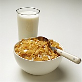 A Bowl of Cornflakes with Milk and a Spoon and a Glass of Milk