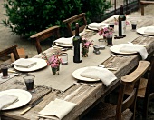 Rustikal gedeckter Tisch mit Rotwein im Freien