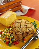 A grilled pork steak with vegetables and bread