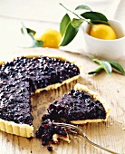 Piece of blueberry tart in front of tart with piece cut
