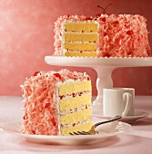 Cherry and coconut cake, slices cut, one slice on plate