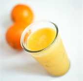 Ein Glas Orangensaft mit zwei ganzen Orangen