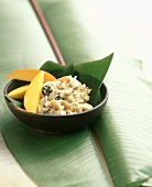 Reispudding mit Mango und Banane auf Bananenblatt