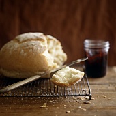 White bread on cake rack with butter; jar of jam