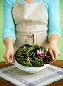A Woman Holding a Bowl of Mixed Salad Greens