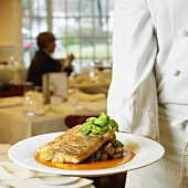 Chef serving red snapper on herb potatoes in restaurant