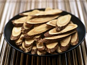 Slices of liquorice root in black bowl