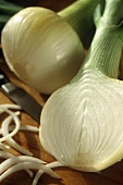 Whole and half white onion on chopping board