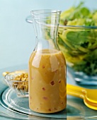 Homemade Salad Dressing in a Carafe with Greens and Nuts
