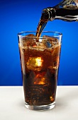 Cola aus Flasche in Glas einschenken