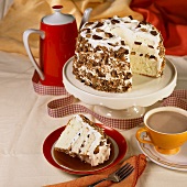 A caramel and cream layer cake, one slice served, and a cup of coffee
