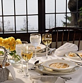 A Tablesetting with Soup and White Wine Next to a Window