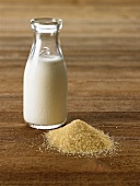 A Bottle of Milk Next to a Pile of Raw Granulated Sugar