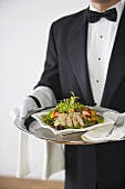 Butler serving chicken salad on silver tray