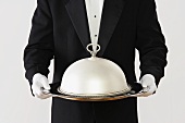 Butler holding a domed silver serving tray