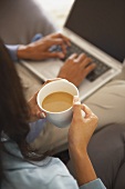 Frau trinkt Kaffee neben Mann am Laptop