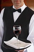 Waiter serving a glass of red wine