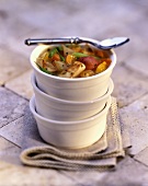 A Stack of White Bowls with Chicken Stew