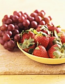 Strawberries in a yellow bowl with red grapes
