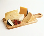 Assorted hard cheeses on wooden cutting board