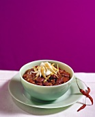 A bowl of chili with cheese and sour cream