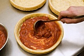 Spreading Tomato Sauce on Pizza Dough with a Ladle