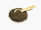 Pile of Celery Seeds with Wooden Spoon on White Background