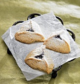 Three Raspberry Filled Cookies with Powdered Sugar on Parchment Paper