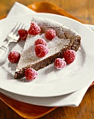 Slice of Chocolate Tart with Raspberries and Powdered Sugar on a Plate