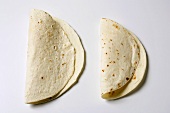 Two folded flour tortillas on white background