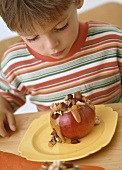 Boy eating apple with nut stuffing and caramel sauce