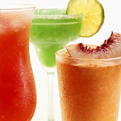 Three frozen cocktails garnished with fruit (close-up)