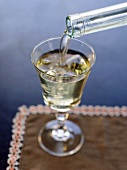 White Wine Pouring From Bottle into Nearly Full Glass