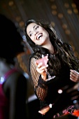 Lachende Frau mit Cocktail im Nachtclub