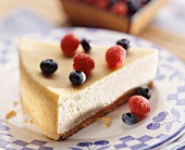 A slice of cheesecake with blueberries and raspberries