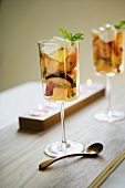 Fruit cocktail with cream & fresh mint in dessert glasses