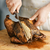 Hands carving roast chicken