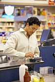 Mann bezahlt mit Kreditkarte an der Kasse im Supermarkt