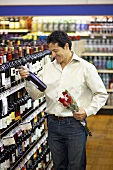 Mann mit Weinflasche und rotem Rosenstrauss im Supermarkt