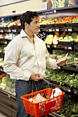 Man with shopping list and basket in a supermarket